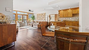 Una cocina moderna con armarios de madera, una mesa de comedor de vidrio y un ventilador de techo.