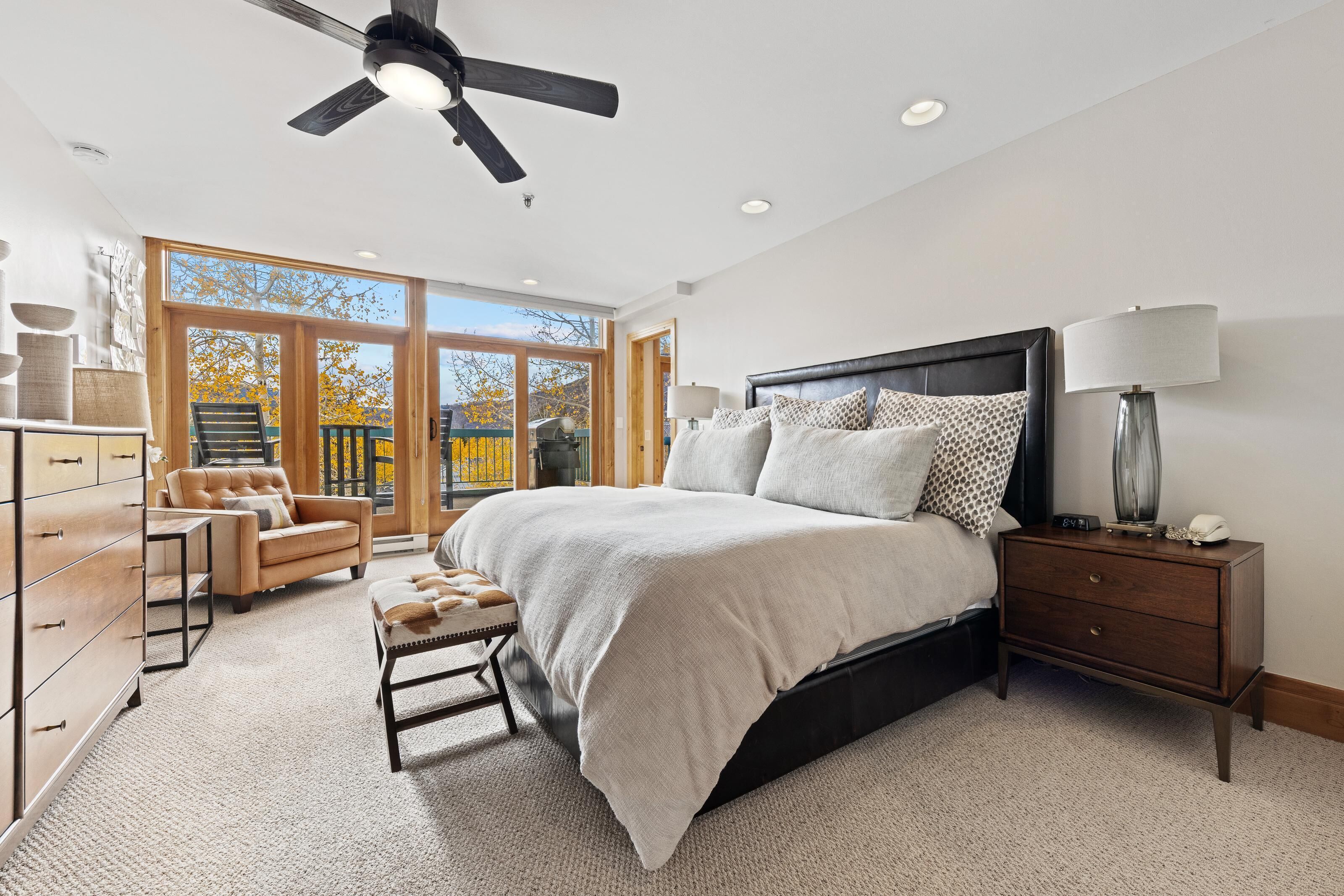 A bedroom with a large bed, a nightstand, a dresser, and a chair.