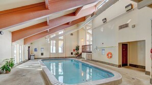 En inomhuspool med kakel runt kanten, träbjälkar i taket och en livboj på väggen.