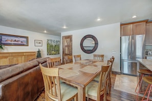 Amplia sala de estar con una mesa de comedor de madera, sofá de cuero y una zona de cocina con electrodomésticos de acero inoxidable.