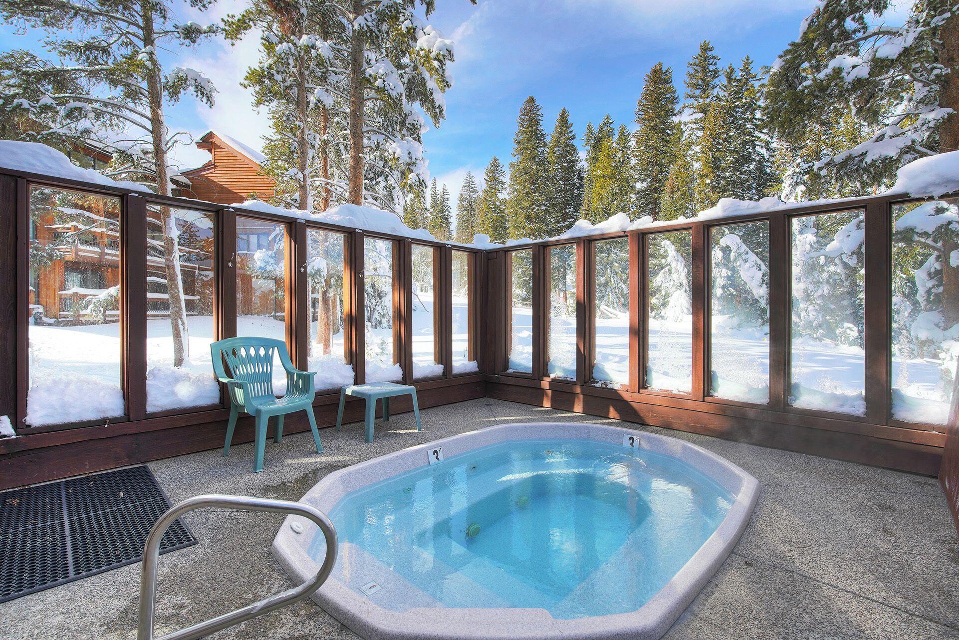 A heated outdoor pool with a view of snow-covered trees and a wooden cabin in the background.