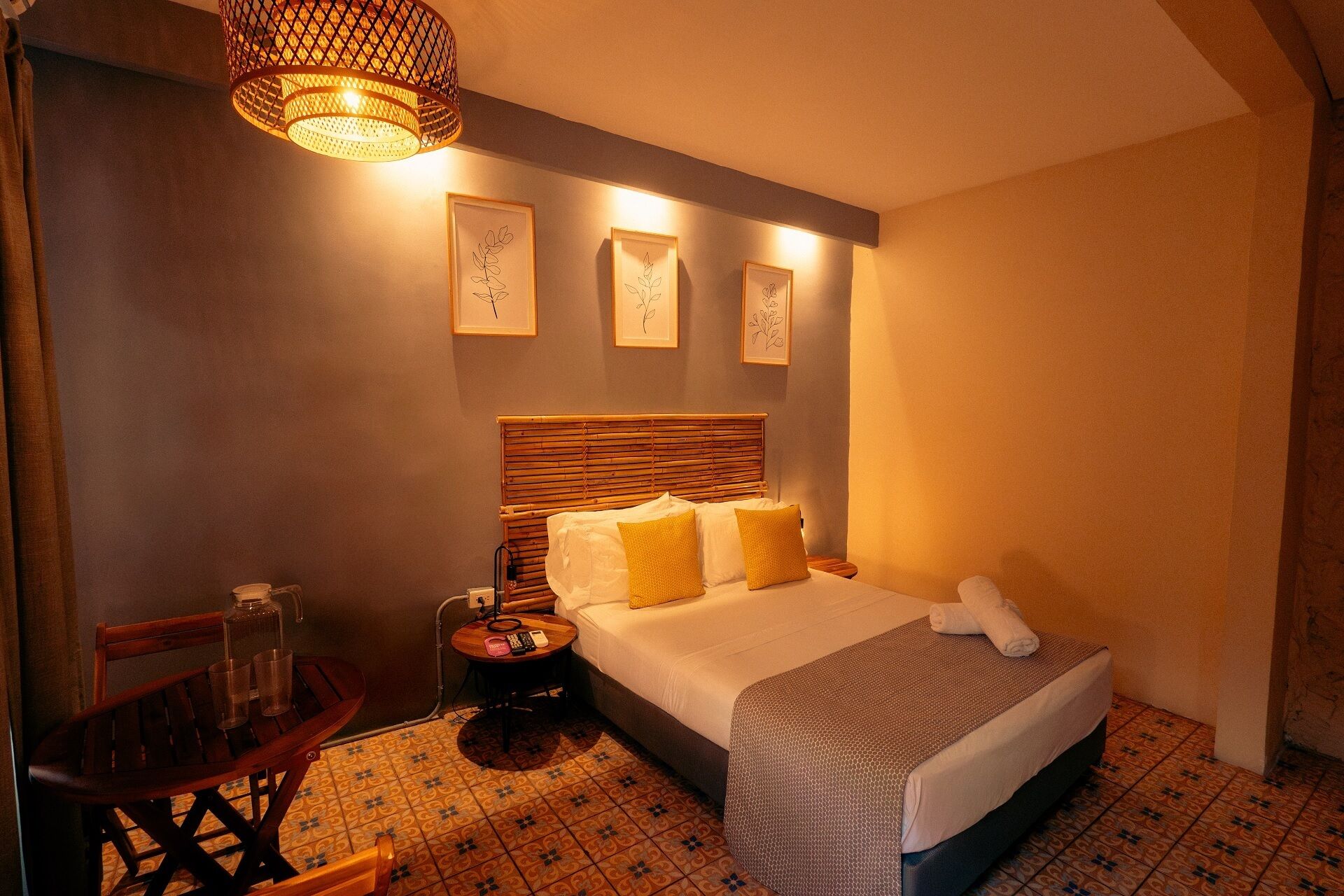 A hotel room with a bed, bedside table, lamp, and wall art.