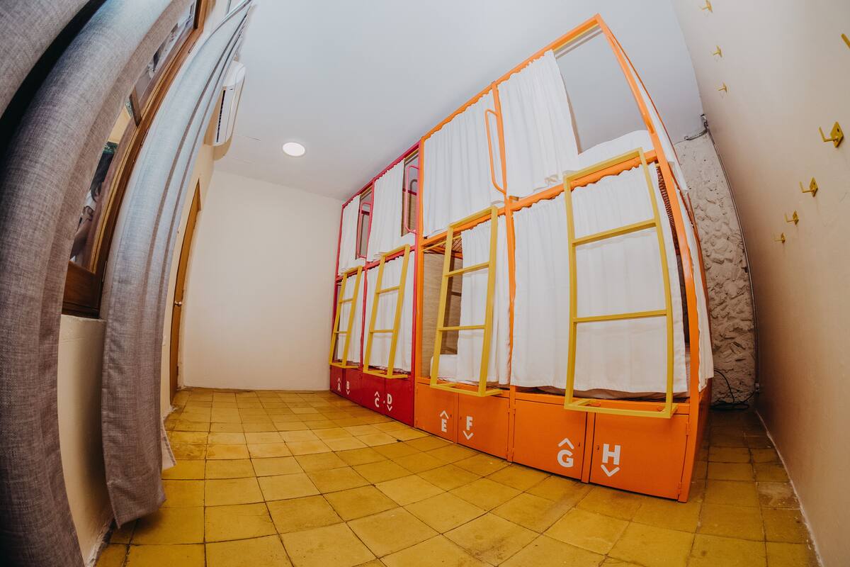 Een kamer met stapelbedden, een betegelde vloer en een luchtverkoeler aan de muur.