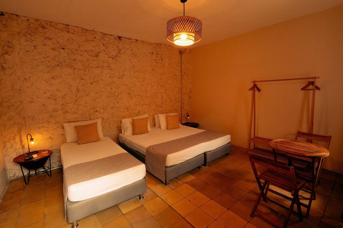 Een kamer met twee bedden, een tafeltje en een hangstoel.