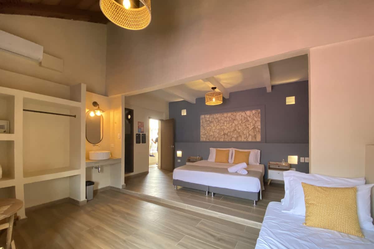 Een ruime slaapkamer met een groot bed, nachtkastjes, een kledingkast, en een badkamer met een wastafel en spiegel.