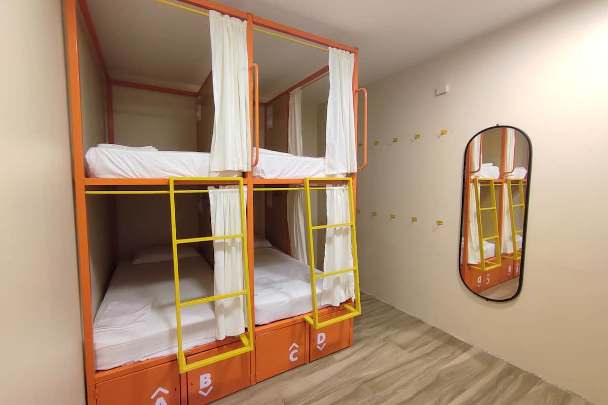 Een stapelbed met een ladder, een spiegel en opbergladen.