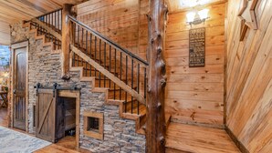 Ein Holzblockhaus-Interieur mit einer Steintreppe, einer Holztür und einem Schild mit den Hausregeln.