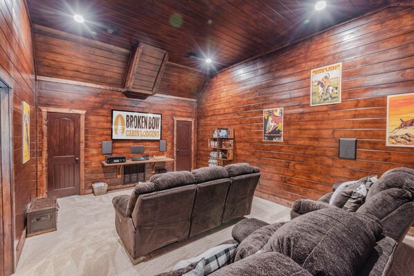 Una habitación acogedora de estilo cabaña con interior de madera, un sofá, un sillón reclinable y un cartel que dice 'Bronken Bow Cabin Lodging'.
