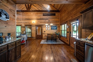 Un intérieur en bois comprenant un coin cuisine, une table à manger et un panneau indiquant la présence d’un café.