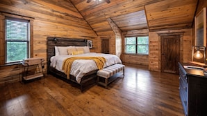 Ein Schlafzimmer einer Holzhütte mit Bett, Bank, Kommode und Deckenventilator.