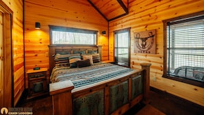 Een chalet met een houten interieur, een bed met decoratieve beddengoed, een wandklok en een kunstwerk met een Texaanse thema.