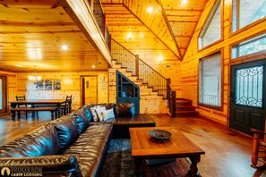 Step up to the upper level via the wooden staircase and relax on the comfortable leather sofa in this inviting cabin.