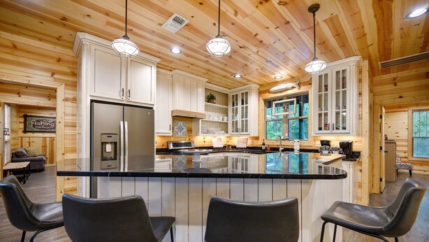A spacious kitchen with a large island, bar stools, and wooden cabinetry.