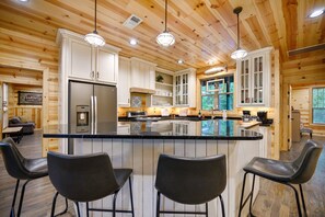 Una cocina amplia con una isla grande, taburetes de bar y armarios de madera.