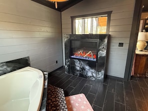 Une salle de bain avec une baignoire blanche, une cheminée en marbre et un banc à motifs à pois.