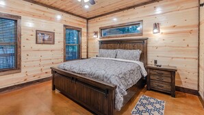 Une chambre à coucher aux murs lambrissés, avec un lit, des tables de chevet et un ventilateur de plafond.