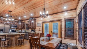 L’intérieur d’un chalet en bois comprend une cuisine, un coin repas et un bar avec des sièges.