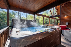 Ein Whirlpool mit aufsteigendem Dampf, umgeben von einer Holzterrasse und Gartenmöbeln.