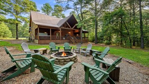 A cabin with a deck, outdoor seating, and a fire pit.