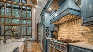 Une cuisine spacieuse dotée d’un grand îlot central, de planchers en bois et d’un mur décoratif en briques.