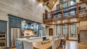 Une cuisine spacieuse dotée d’un grand îlot central, de planchers en bois et d’un espace en mezzanine avec balcon.