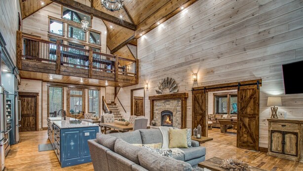 Un vaste espace de vie doté d’un haut plafond, de parquets en bois, d’une cheminée et d’un grand canapé.