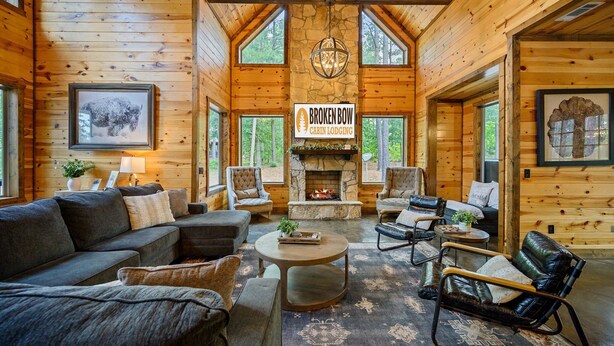 A log cabin interior with a fireplace, wooden walls, and a cozy seating area.