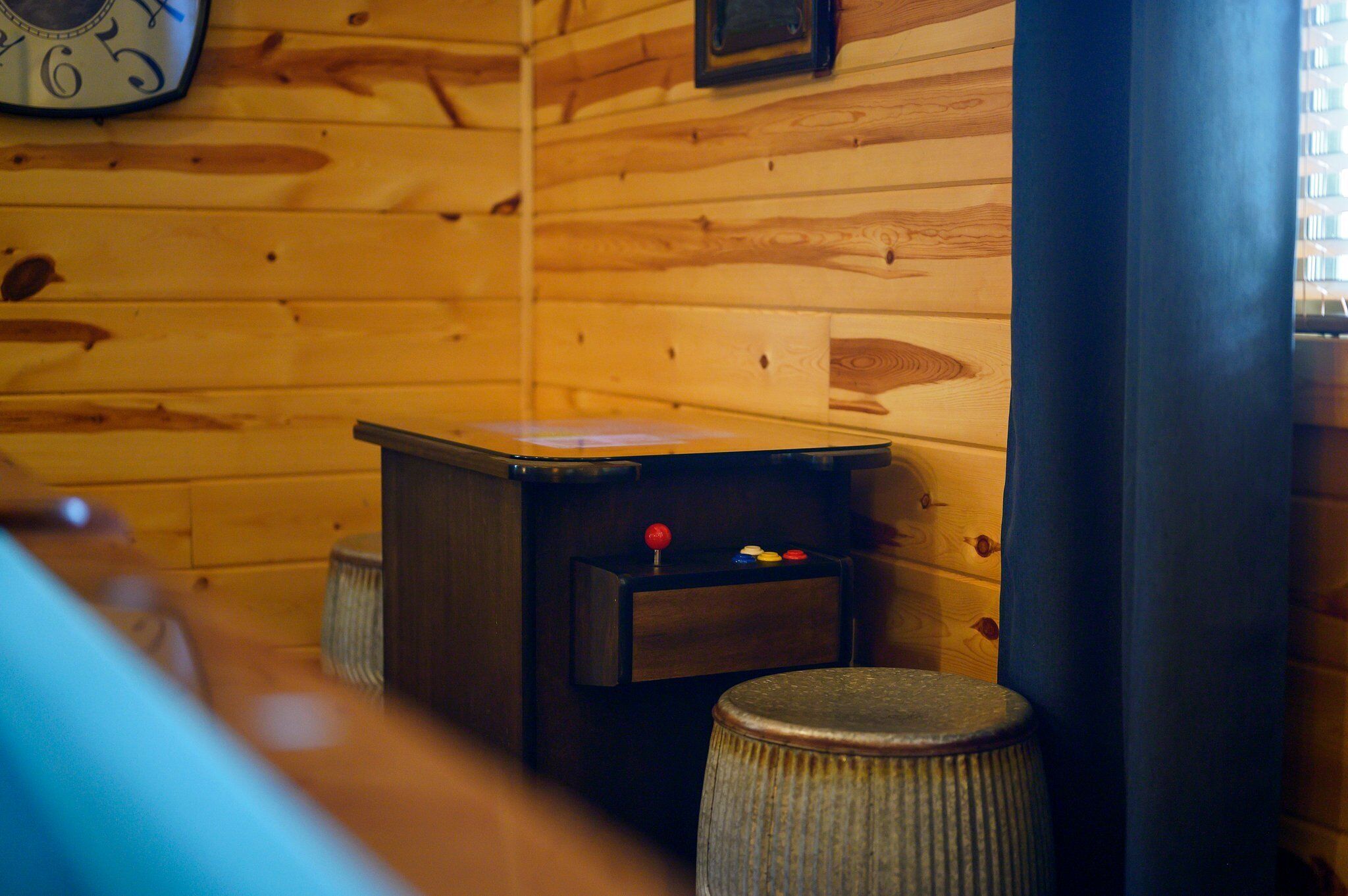 A wooden interior with a small table, a stool, and a clock on the wall.