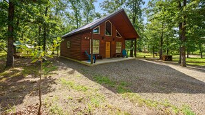 Une cabane en bois, dotée d’un toit à pente, entourée d’arbres.