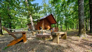 Un chalet rustique doté d’un foyer extérieur et de sièges pour se détendre en plein air.