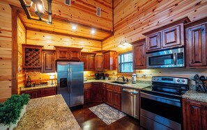A modern kitchen with wooden cabinets, stainless steel appliances, granite countertops, and a built-in wine cooler.