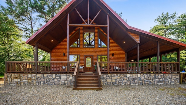 A log cabin with a stone foundation, wooden exterior, and a covered porch.