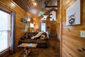 Relax in a cozy cabin-style interior with a plush sofa, rustic table, and framed artwork.