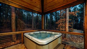 A hot tub in a wooden cabin with a forest view.