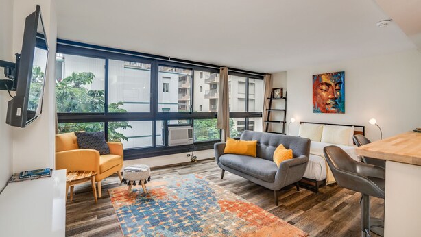 Ein modernes Wohnzimmer mit Sofa, Sessel und Essbereich.