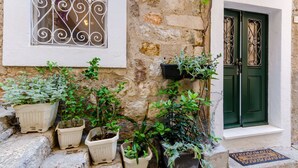 Un bâtiment en pierre doté d’une fenêtre ornée de barreaux en fer décoratifs et d’une porte verte présentant des motifs similaires en fer forgé.