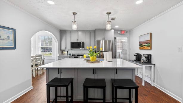 Una cocina moderna con una isla central, taburetes de bar e iluminación colgante.