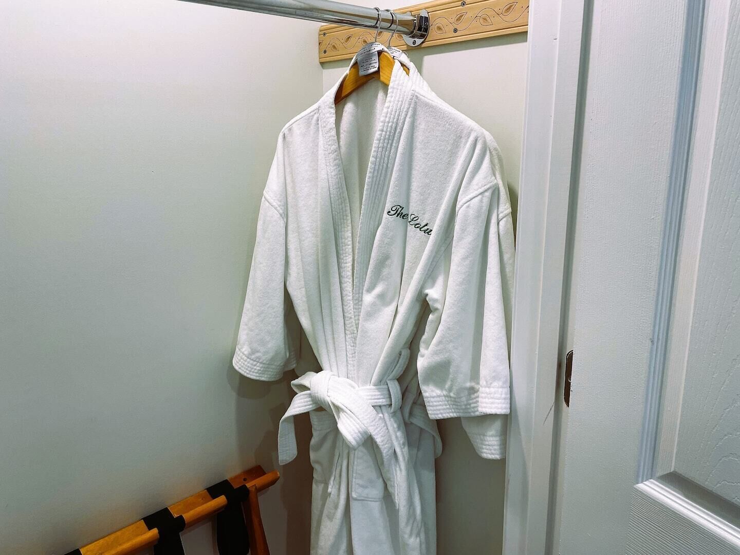 Una bata blanca colgada en una percha de madera en un baño.