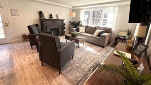 A living room with a fireplace, sofa, armchairs, and a coffee table.