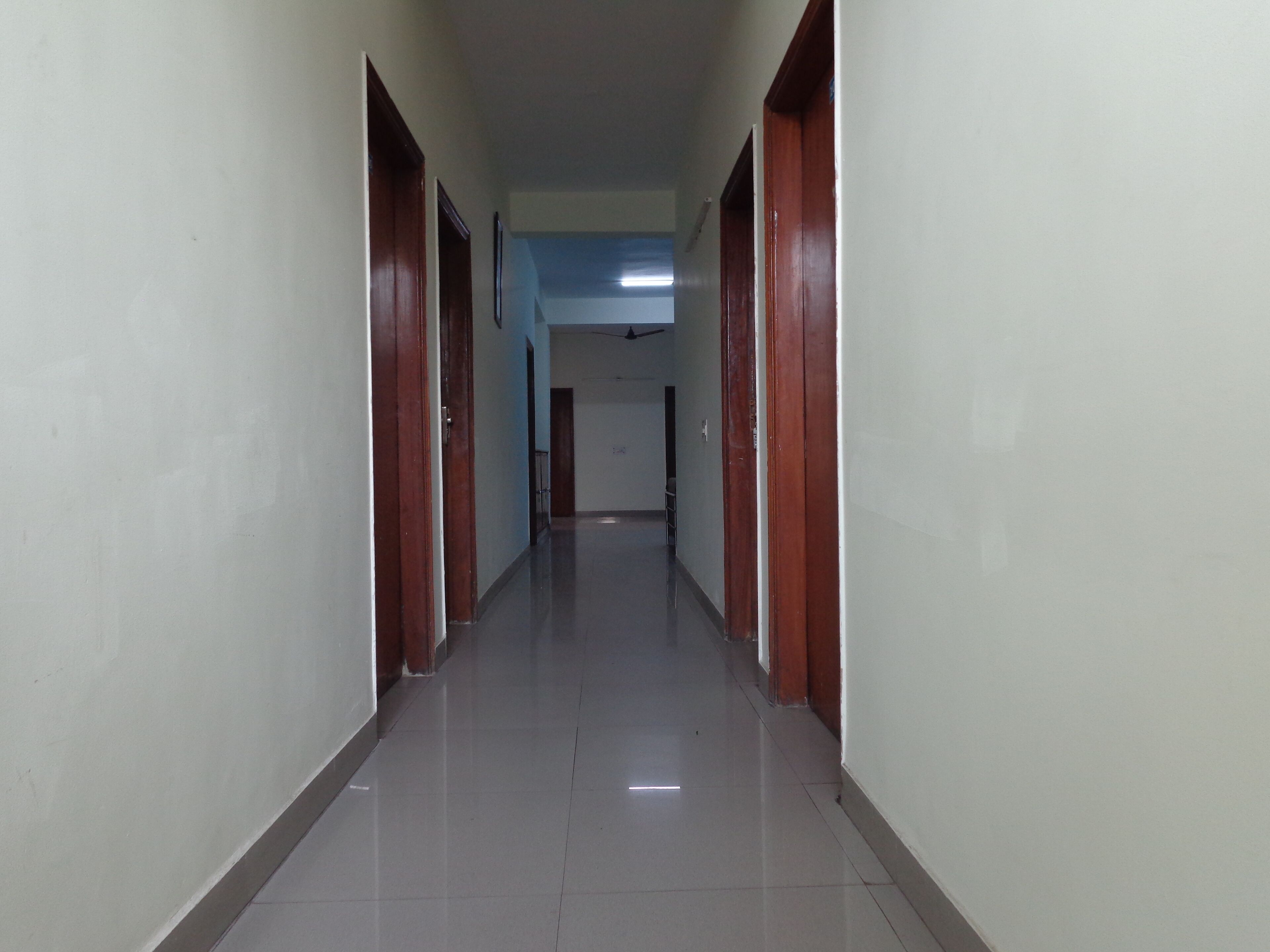 A long, narrow hallway with wooden doors on both sides and a tiled floor.