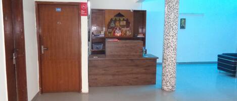A reception area with a wooden desk, a pillar, and a blue-lit wall.