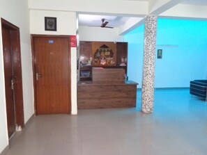 A reception area with a wooden desk, a pillar, and a blue-lit wall. - Hotel Akash Palace (Noida)