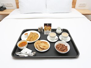 A breakfast tray with various dishes including flatbread, soup, and coffee on a bed in a hotel room. - Hotel Akash Palace (Noida)