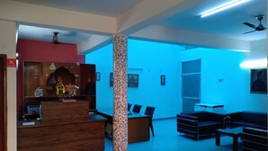 Zona de recepción con un escritorio de madera, un pilar y asientos.