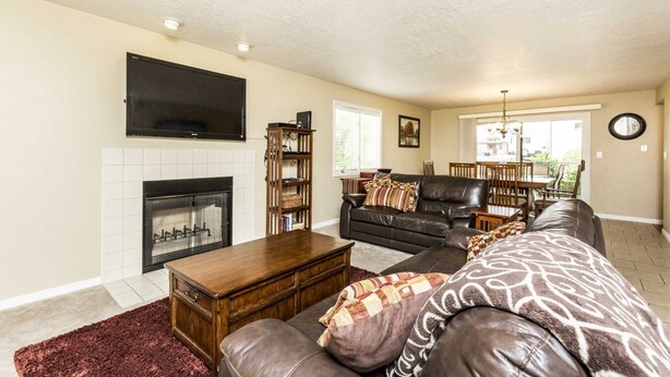 A living room with a fireplace, a television, a sofa, a coffee table, and a dining area with a table and chairs.