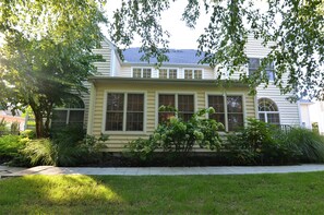 A two-story house with a front porch, large windows, and a well-maintained lawn.
