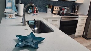 A modern kitchen with white cabinets, a stainless steel sink, a microwave, and an oven. - Escape to your HAPPY place, luxury corner condo right on the beach! (Jensen Beach)