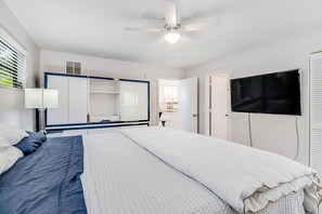 Ein Schlafzimmer mit Bett, Deckenventilator, Fernseher und Kleiderschrank.