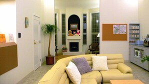 A living room with a sofa, a coffee machine, a plant, and a fireplace. - Family Lodge Hatagoya Chiba Katsuura (Katsuura)