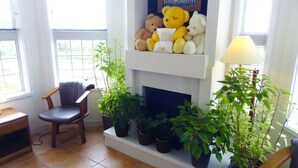 A cozy living room with a fireplace, a chair, and several potted plants. - Family Lodge Hatagoya Chiba Katsuura (Katsuura)